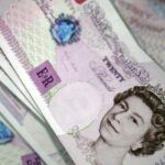 Close-up of several British £20 banknotes, featuring the Queen's portrait. The notes are fanned out.