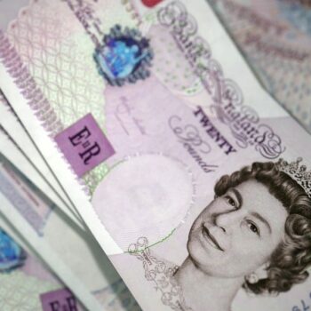 Close-up of several British £20 banknotes, featuring the Queen's portrait. The notes are fanned out.
