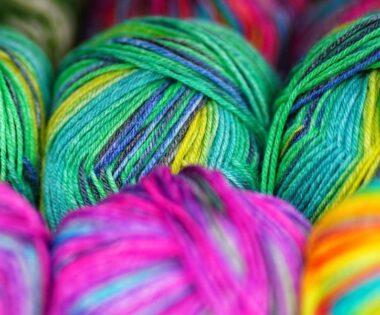 Brightly colored wool in greens, pinks, and yellows are tightly packed, showcasing vibrant colours and textures, conveying a lively, creative atmosphere.