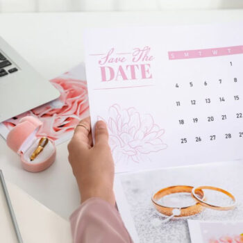 An elegant image, with soft pink colours, featuring a laptop, calendar, notebook and pen.