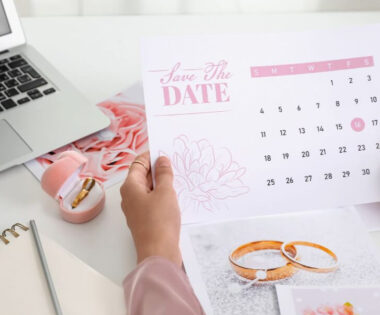 An elegant image, with soft pink colours, featuring a laptop, calendar, notebook and pen.