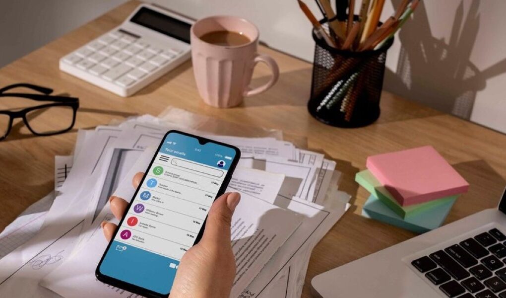 Workspace with a laptop and coffee cup and a items illustrating a visual guide on how to manage finances through smartphone mobile apps, featuring an app with budgeting tools.